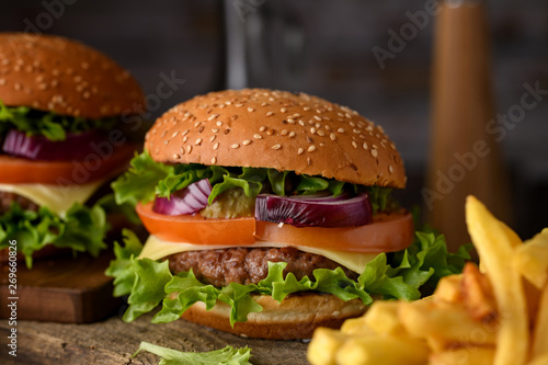 Home cooking burgers and french fries with your hands on a dark wooden background.