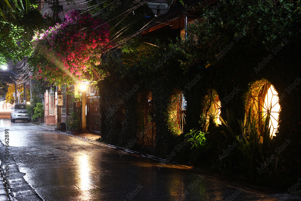 Naklejka premium View on a night street of city with lantern and moving transport in a rainy weather. Long exposure. Chiang Mai, Thailand.
