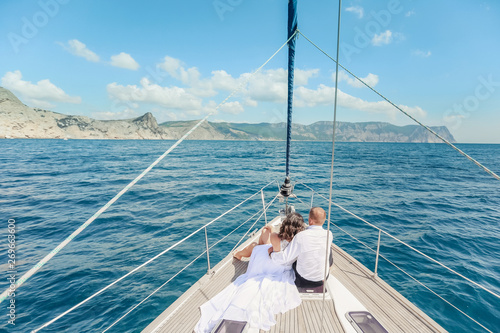Young Couple Relaxing on a Yacht. Happy wealthy man and a woman by private boat have sea trip.