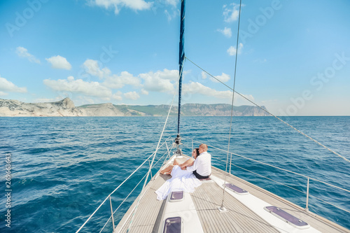 Young Couple Relaxing on a Yacht. Happy wealthy man and a woman by private boat have sea trip. © ElenaBatkova