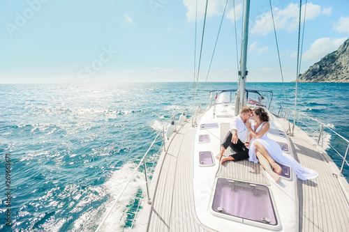 Young Couple Relaxing on a Yacht. Happy wealthy man and a woman by private boat have sea trip.