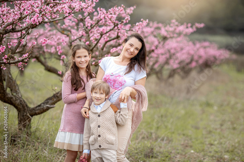 Young Beautiful Mother at Spring, Pink Blooming Tree at the Background.