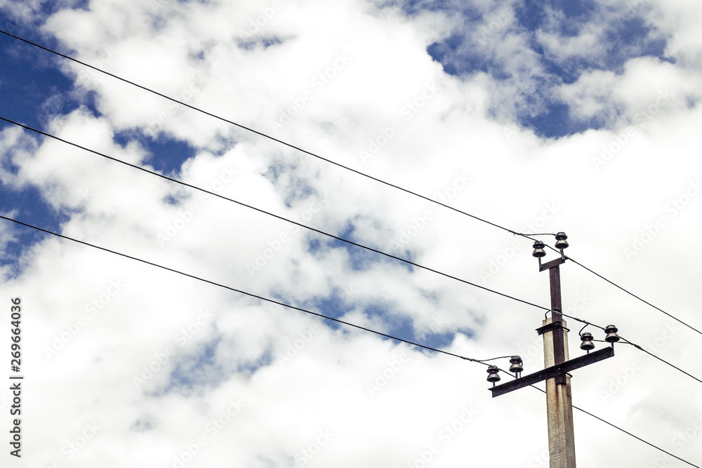 Fototapeta premium high voltage wires and an electrical pole between them are located under a picturesque sky with thick clouds