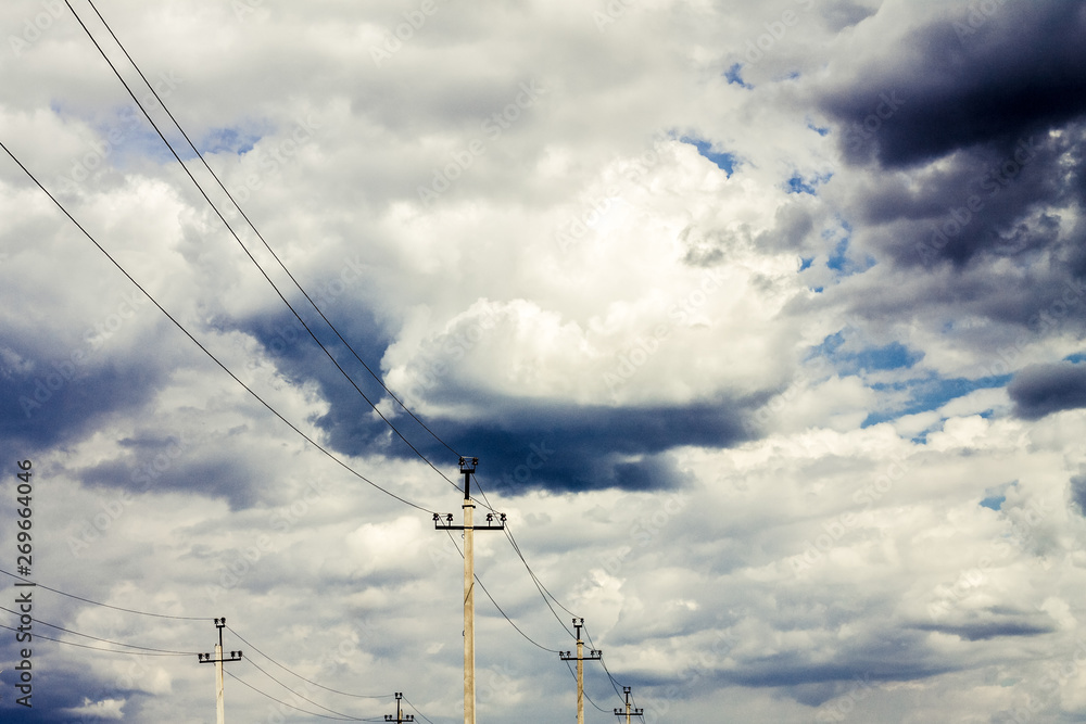 against the sky with thick clouds are high-voltage wires and poles between them