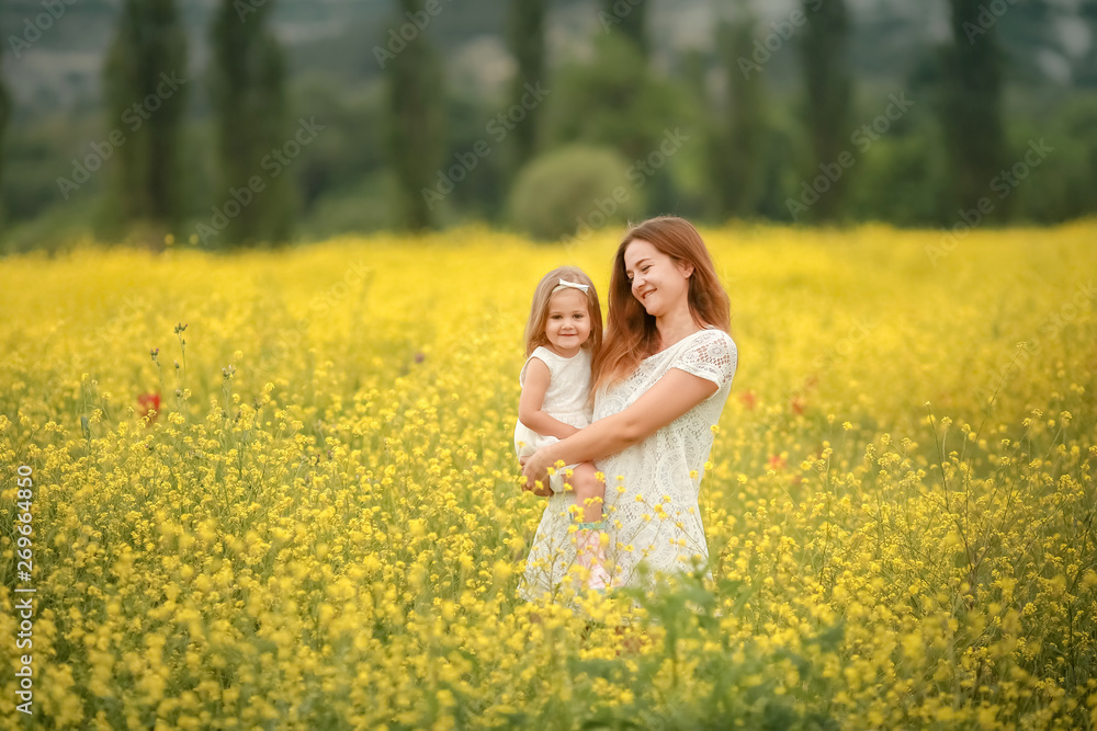 Happy mother and daughter child together with yellow dandelion flowers in summer day Happy mother and daughter child together with yellow dandelion flowers in summer day