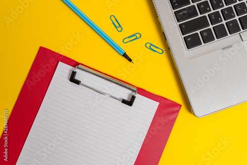 Open laptop clipboard blank paper sheet marker clips colored background