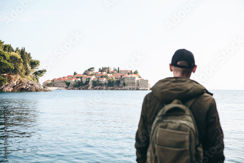 Wallpaper Mural TView of the island of Sveti Stefan in Montenegro. The tourist looks at it. Selective focus. The man is blurred. Torontodigital.ca