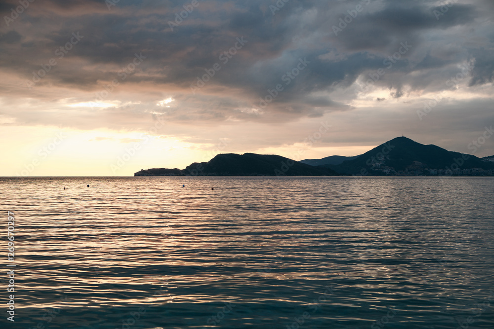 Beautiful view of the sunset and the natural landscape with the sea and hills or mountains in Montenegro in the summer.