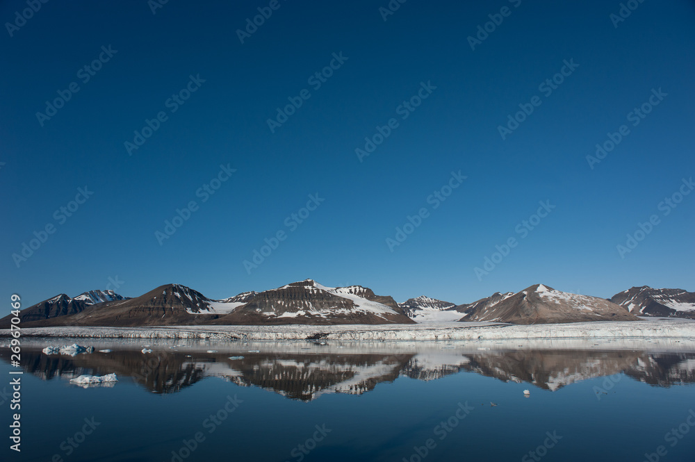 Northern arctic mountains with still water and blue sky shows a lack of ice due to melting and climate crisis. Copy Space. tony skerl