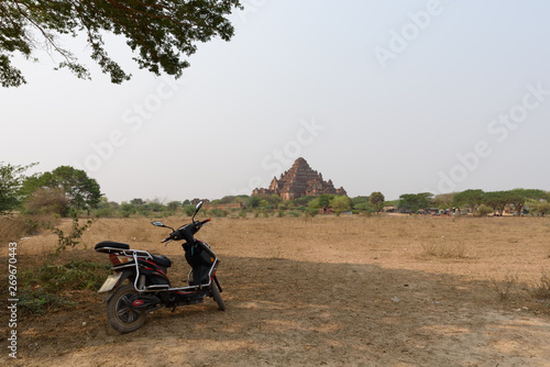 E-Bike parked under tree with Dhammayangyi Temple in the background, Bagan, Myanmar