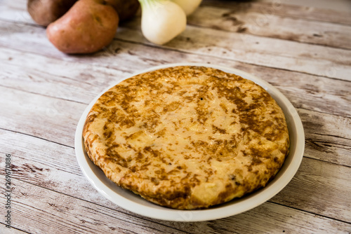 Traditional Spanish omelette. Spanish Tortilla on wooden background with potatoes and onion