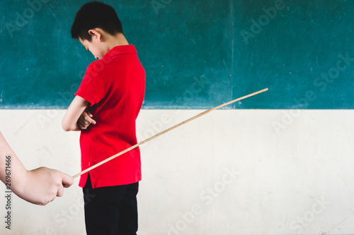 Students being physically punished by teacher with small wooden stick