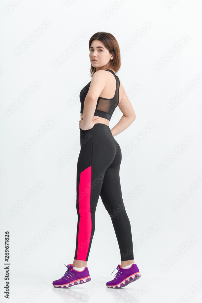 Woman with dark hair in a sportswear stretching in a gym. Exercising for weight loss Woman with dark hair in a sportswear stretching in a gym. Exercising for weight loss