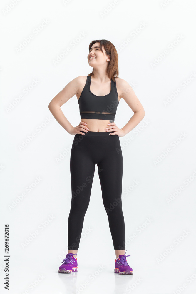 Woman with dark hair in a sportswear stretching in a gym. Exercising for weight loss Woman with dark hair in a sportswear stretching in a gym. Exercising for weight loss