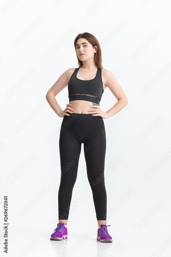Woman with dark hair in a sportswear stretching in a gym. Exercising for weight loss Woman with dark hair in a sportswear stretching in a gym. Exercising for weight loss