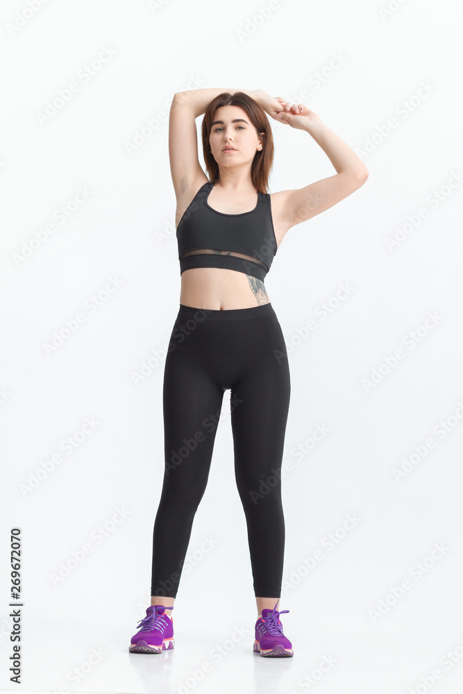Woman with dark hair in a sportswear stretching in a gym. Exercising for weight loss Woman with dark hair in a sportswear stretching in a gym. Exercising for weight loss
