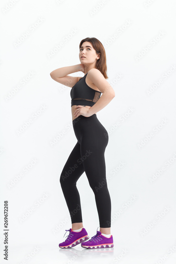 Woman with dark hair in a sportswear stretching in a gym. Exercising for weight loss Woman with dark hair in a sportswear stretching in a gym. Exercising for weight loss