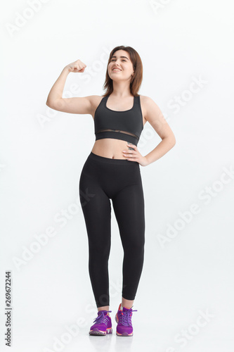 Woman with dark hair in a sportswear stretching in a gym. Exercising for weight loss