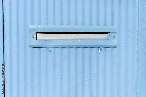 Old letterbox or mailbox in the retro abstract blue metal gate door traditional way of delivering letters and mail to the house close up