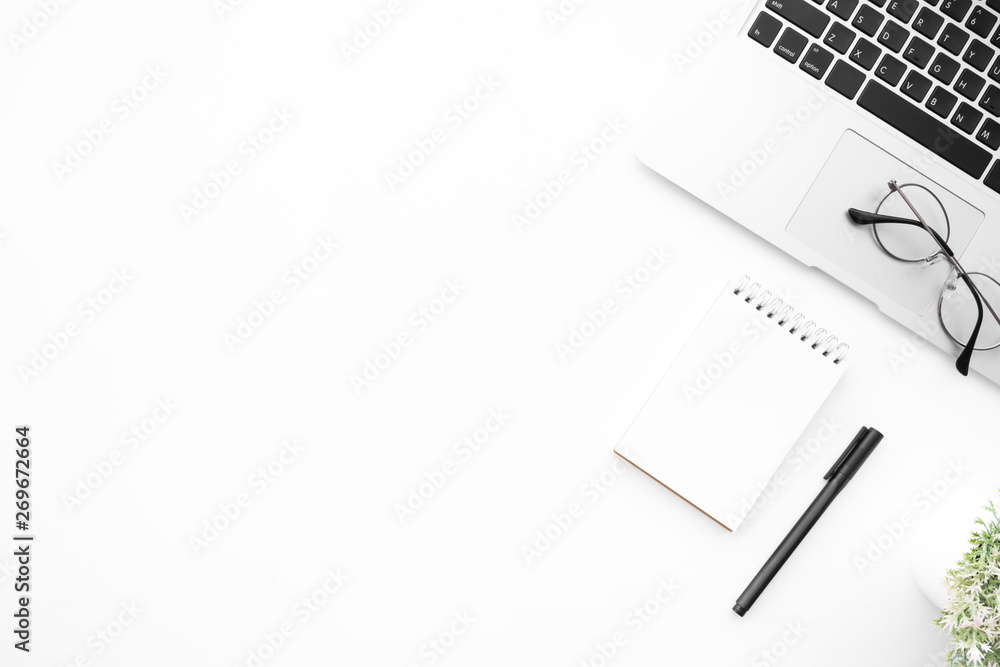White office desk table with laptop computer, blank notebook, pen and supplies. Top view with copy space, flat lay. White office desk table with laptop computer, blank notebook, pen and supplies. Top view with copy space, flat lay.