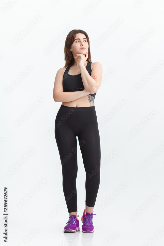 Woman with dark hair in a sportswear stretching in a gym. Exercising for weight loss Woman with dark hair in a sportswear stretching in a gym. Exercising for weight loss