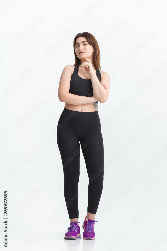 Woman with dark hair in a sportswear stretching in a gym. Exercising for weight loss Woman with dark hair in a sportswear stretching in a gym. Exercising for weight loss