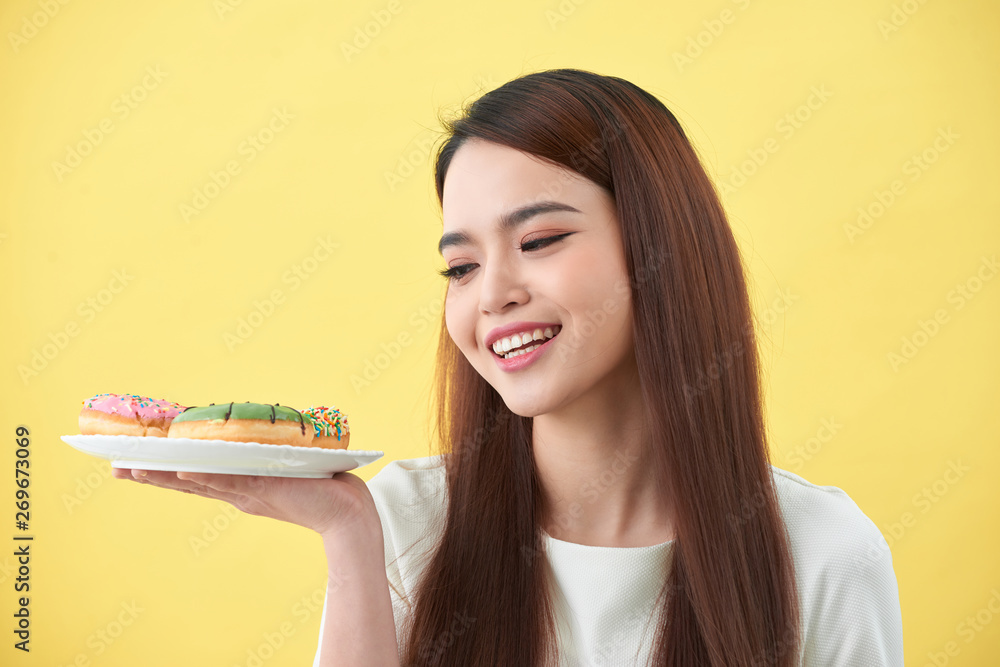 Beautiful young woman smiling holding a plate full of delicious color donuts Beautiful young woman smiling holding a plate full of delicious color donuts