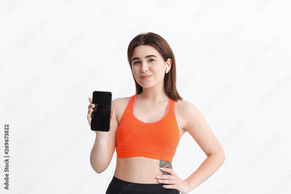 Young fitness woman posing isolated on a white background listening to music with wireless headphones. Young fitness woman posing isolated on a white background listening to music with wireless headphones.