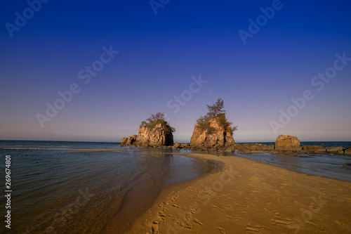 Amazing sunset at the tropical beach island with 2 nature rock formation by the sea.