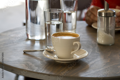 A cup of cappuccino coffee and drinking clean water on a coffee table in a cafe