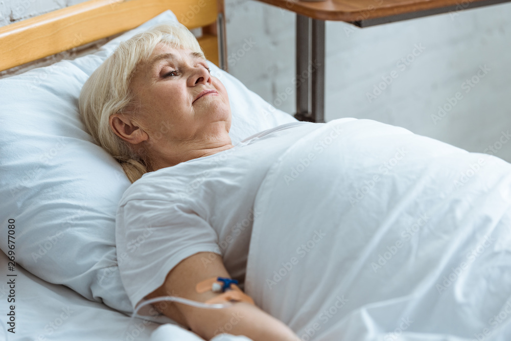 sick senior woman with grey hair on bed in clinic sick senior woman with grey hair on bed in clinic