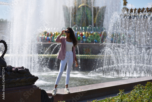 brunette girl in white pants by the fountain