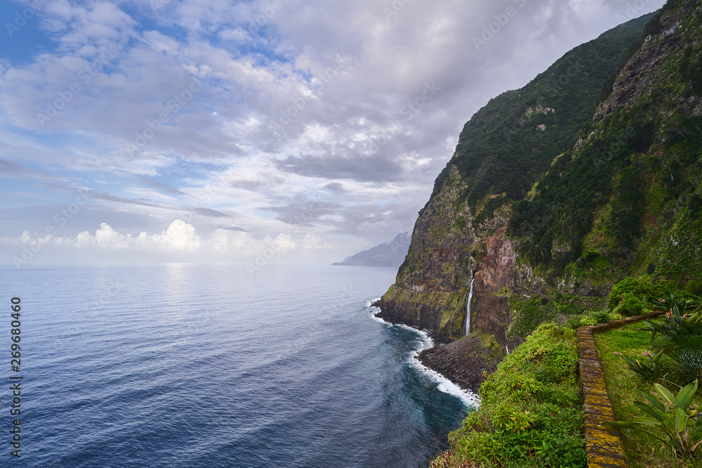 Beautiful view of a waterfall near the blue atlantic ocean and nice sky in Madeira