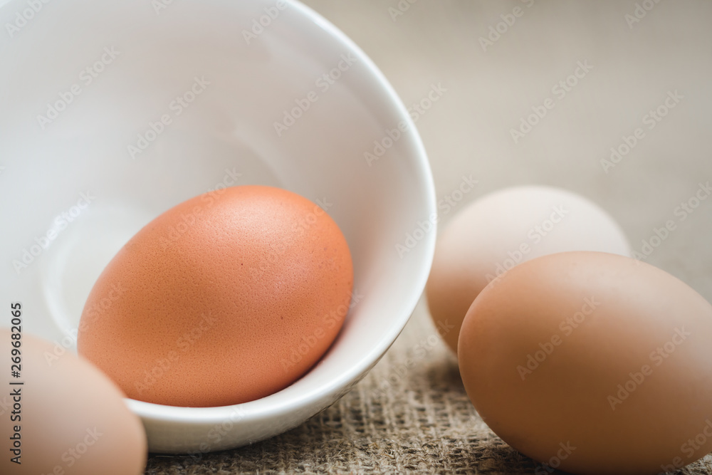 White and light brown chicken eggs in white dishes and on linen fabric, soft focus White and light brown chicken eggs in white dishes and on linen fabric, soft focus