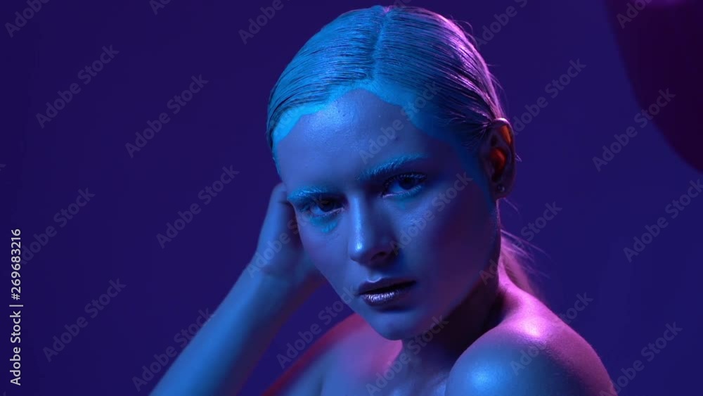 Beautiful female model posing in blue and pink neon light in studio Beautiful female model posing in blue and pink neon light in studio