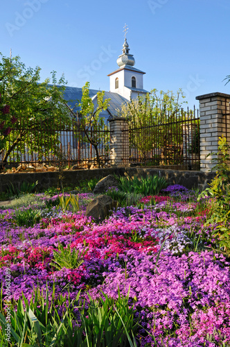 Landscape design around the church with beautiful flowers on the background of the blue sky