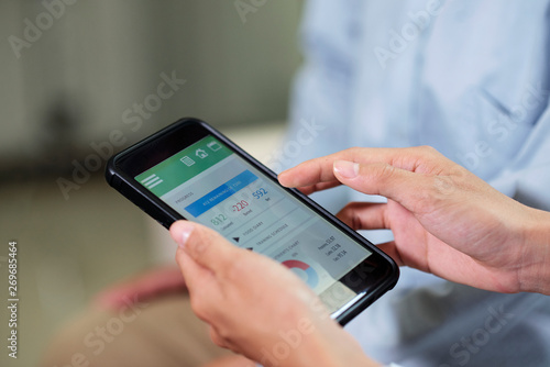 Close-up of woman using her smartphone she sitting and looking at results of her health in mobile application