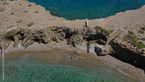 Aerial drone photo of iconic deep turquoise beach of Latinaki with crystal clear sea and rocky sea shore forming small caves, Folegandros island, Cyclades, Greece photo