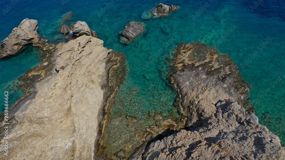 Aerial drone photo of iconic deep turquoise beach of Latinaki with crystal clear sea and rocky sea shore forming small caves, Folegandros island, Cyclades, Greece