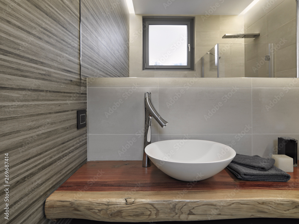 interior shot of a modern bathroom in the foreground the counter top washbasin on the wooden top interior shot of a modern bathroom in the foreground the counter top washbasin on the wooden top