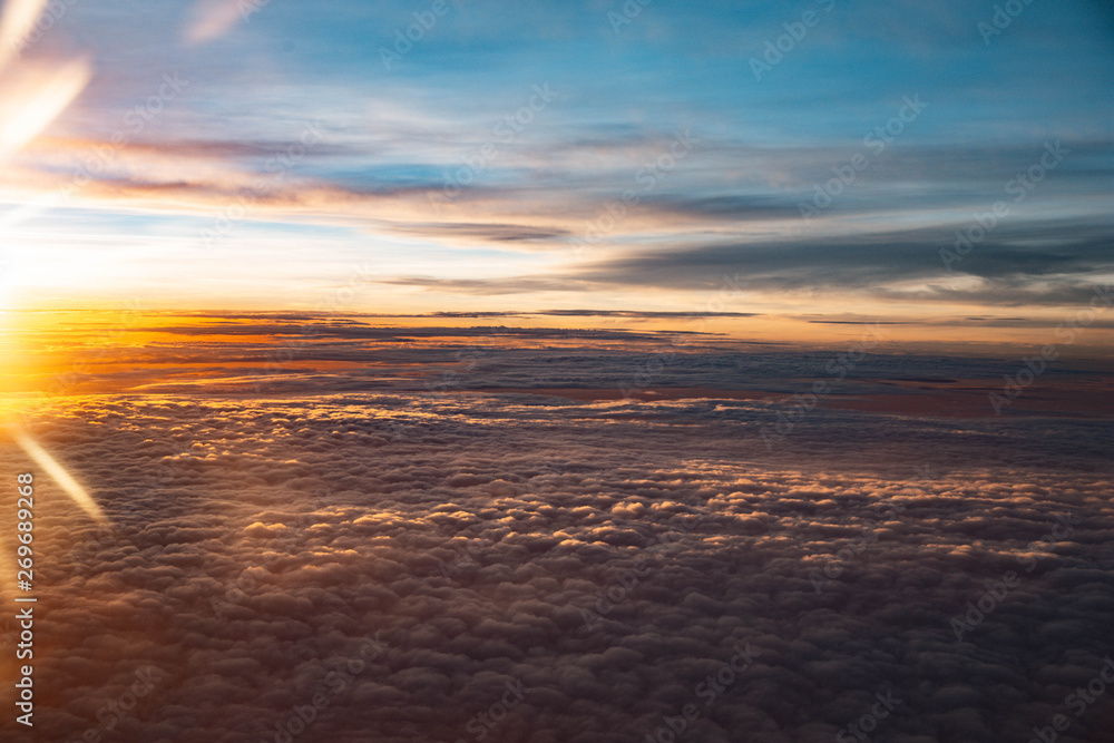 Beautiful sunshine sky above clouds with dramatic light. Cabin view from airplane.