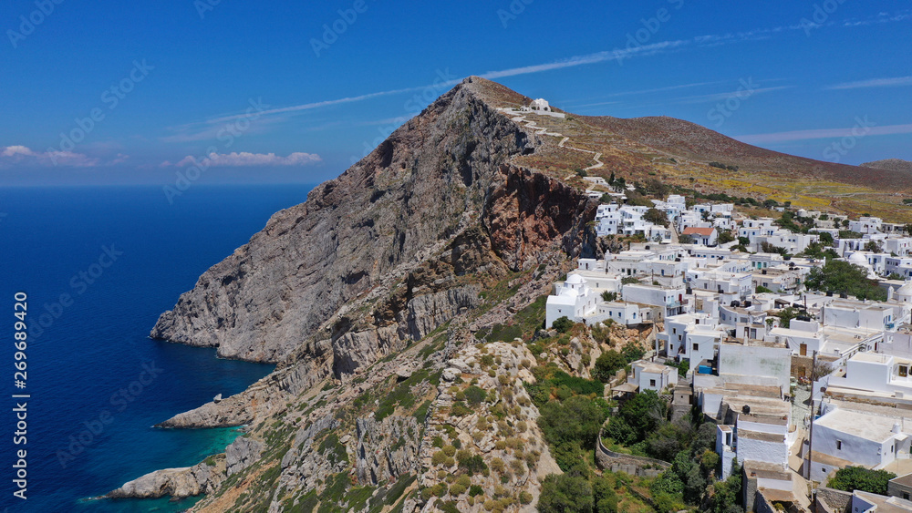 Obraz premium Aerial drone photo of iconic and picturesque main village (chora) of Folegandros island featuring castle and built on top of steep hill overlooking the Aegean blue sea, Cyclades, Greece