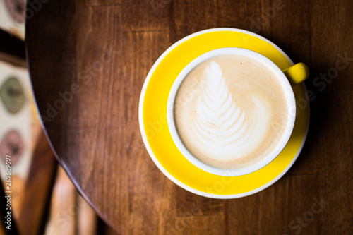 Yellow cup of aromatic coffee on a wooden table.