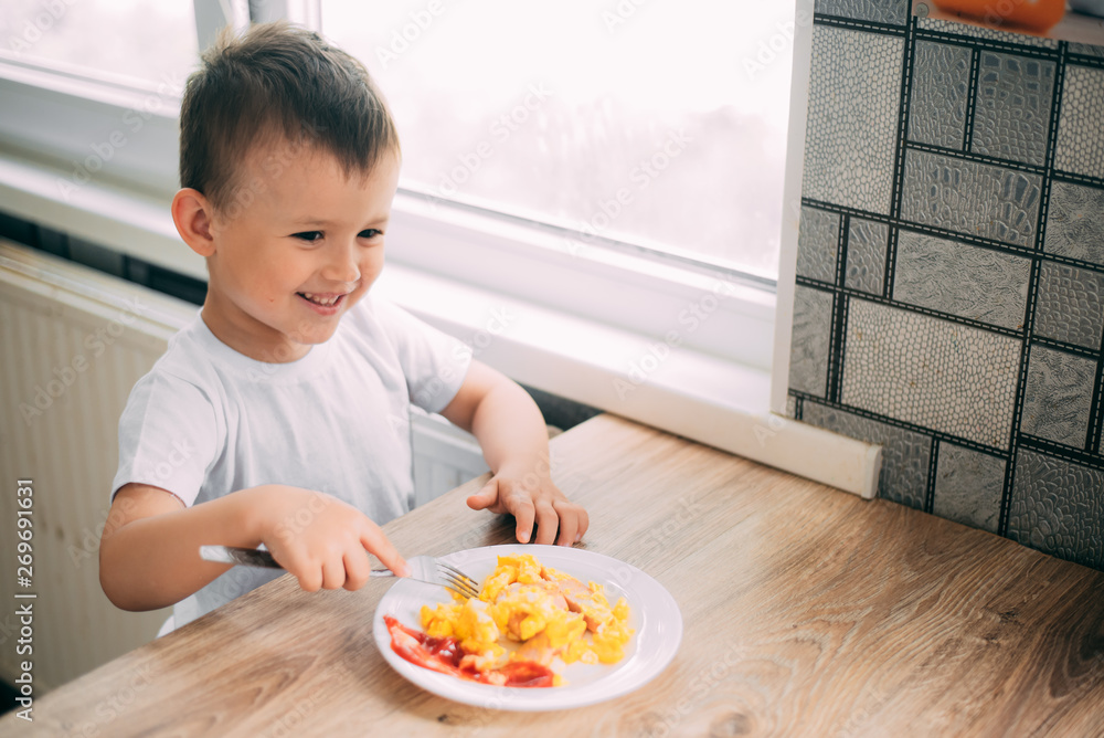child day in the kitchen eating an omelet with sausage and ketchup child day in the kitchen eating an omelet with sausage and ketchup