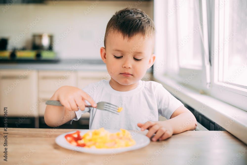 child day in the kitchen eating an omelet with sausage and ketchup child day in the kitchen eating an omelet with sausage and ketchup
