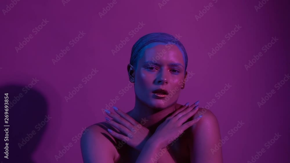 Beautiful female model posing in blue and pink neon light in studio Beautiful female model posing in blue and pink neon light in studio