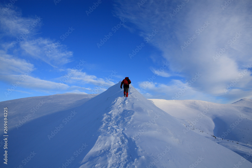 The tourist stands on the ridge of the mountains in the winter mountains