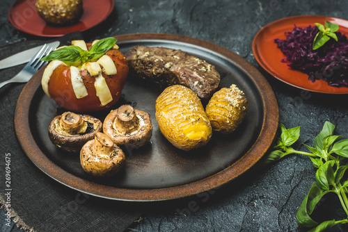 grilled autumn dinner, steak, baked tomato with cheese, baked potatoes with garlic and mushrooms