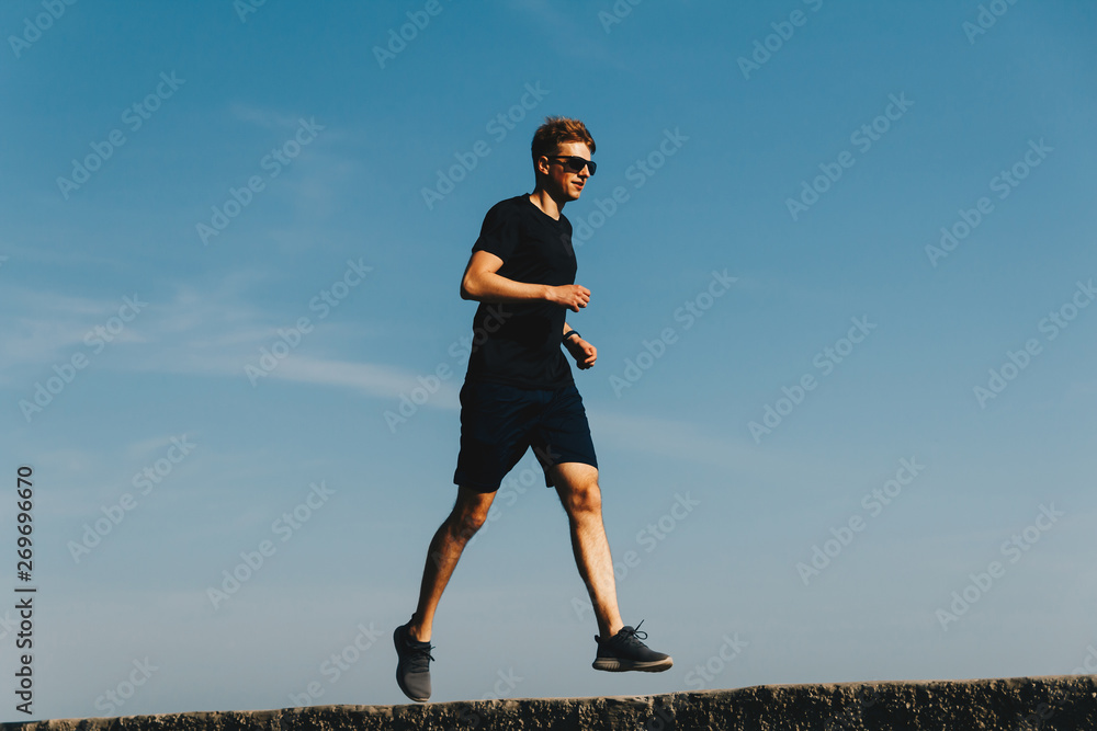 Young running man on sky background at sunrise Young running man on sky background at sunrise