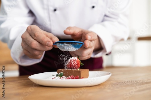 Obraz na płótnie Close up pastry chef decoration delicious dessert dish, serving for customers in bakery, garnishing dessert plate in commercial kitchen